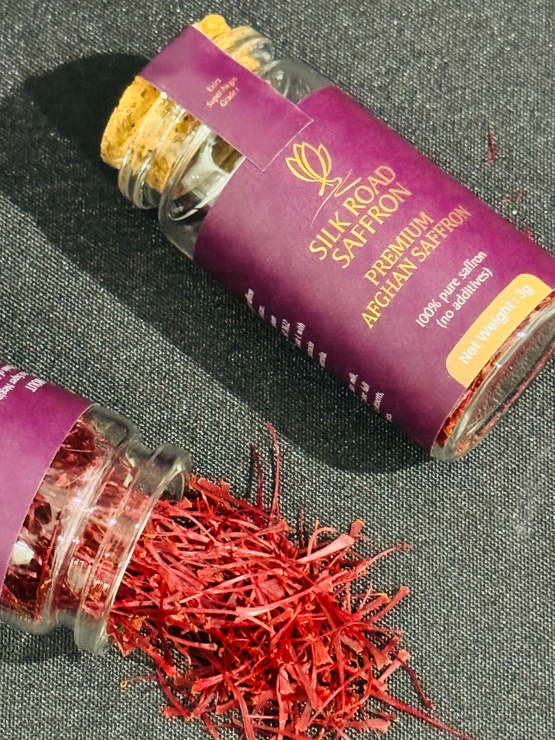 Silk Road Saffron 3g glass jar filled with deep red Afghan saffron threads on a dark textured surface.