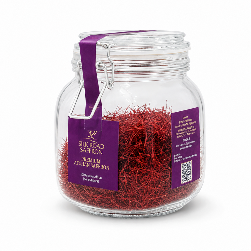 A clear glass jar filled with bright red saffron threads, sealed with a purple clamp strap and labeled 'Silk Road Saffron Premium Afghan Saffron' on a white background.